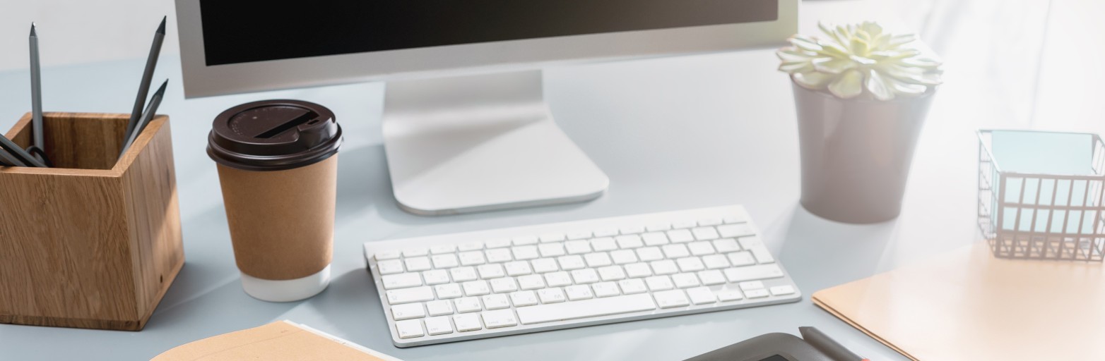 The desk with laptop, notepad with blank sheet, pot of flower, stylus and tablet for retouching. Workspace of professional retoucher. Creativity, design, art and modern equipments concept